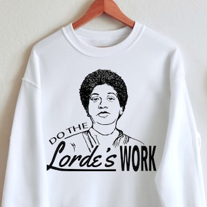 May include: White sweatshirt with a black and white illustration of a woman with the text "Do the Lord's Work" printed on the front.