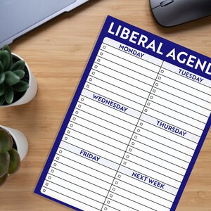 K&ouml;nnte beinhalten: Ein blauer Notizblock mit dem Text "Liberal Agenda" in wei&szlig; gedruckt. Der Notizblock ist in Wochentage unterteilt, mit Platz zum Schreiben von Aufgaben oder Notizen.