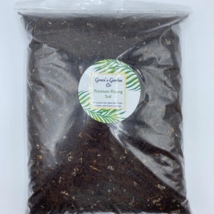 May include: A clear plastic bag filled with dark brown potting soil. The bag has a white label with the text "Grace's Garden Co. Premium Potting Soil Coconut coir, pine bark fines, pumice, and worm castings."