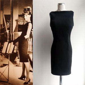 K&ouml;nnte beinhalten: Ein schwarzes, &auml;rmelloses Kleid mit einem Boot Ausschnitt und einer figurbetonten Silhouette. Das Kleid befindet sich auf einer Schaufensterpuppe und wird vor einem wei&szlig;en Hintergrund pr&auml;sentiert.