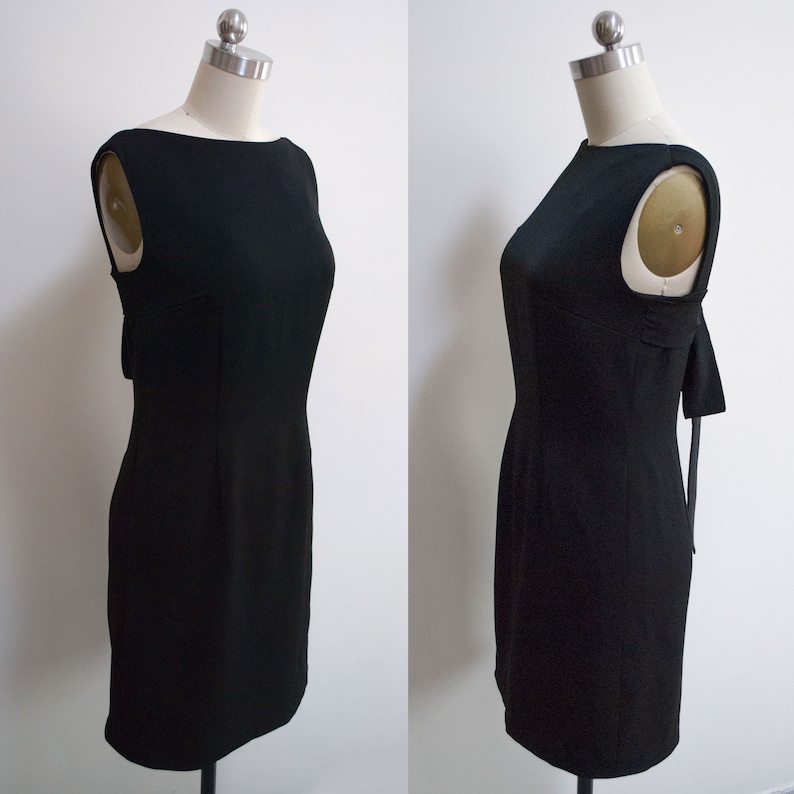 K&ouml;nnte beinhalten: Ein schwarzes &auml;rmelloses Kleid mit einem runden Ausschnitt und einer figurbetonten Silhouette. Das Kleid hat eine Schleife auf der R&uuml;ckseite.