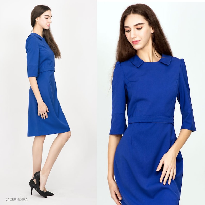 May include: A royal blue dress with a white collar and three-quarter sleeves. The dress has a fitted bodice and a slightly flared skirt.