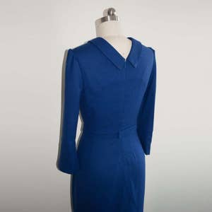 May include: A royal blue dress with a collared neckline and long sleeves. The dress has a fitted bodice and a skirt that falls to the knees.