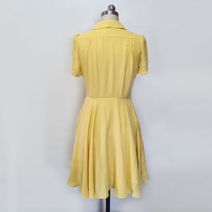 May include: A yellow short-sleeved dress with a collared neckline and a flared skirt.