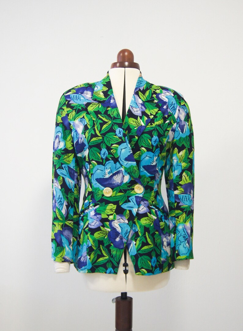 May include: A double-breasted blazer with a vibrant floral print featuring blue, green, and purple flowers on a black background.