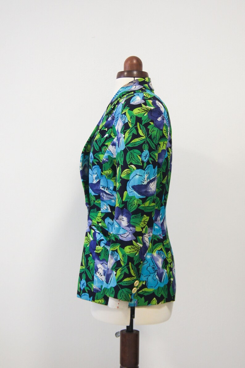 May include: A black blazer with a floral print featuring blue and green flowers on a dark background.