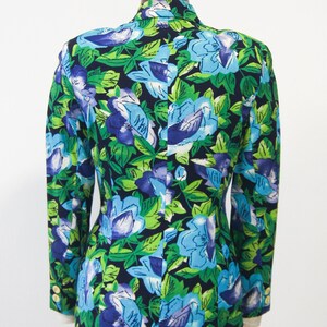May include: A black blazer with a floral print featuring blue, green, and purple flowers on a dark background.