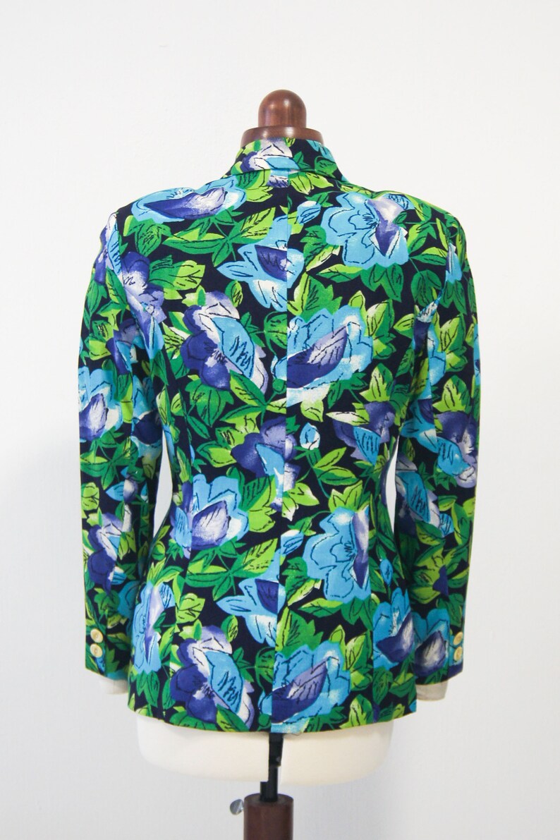 May include: A black blazer with a floral print featuring blue, green, and purple flowers on a dark background.