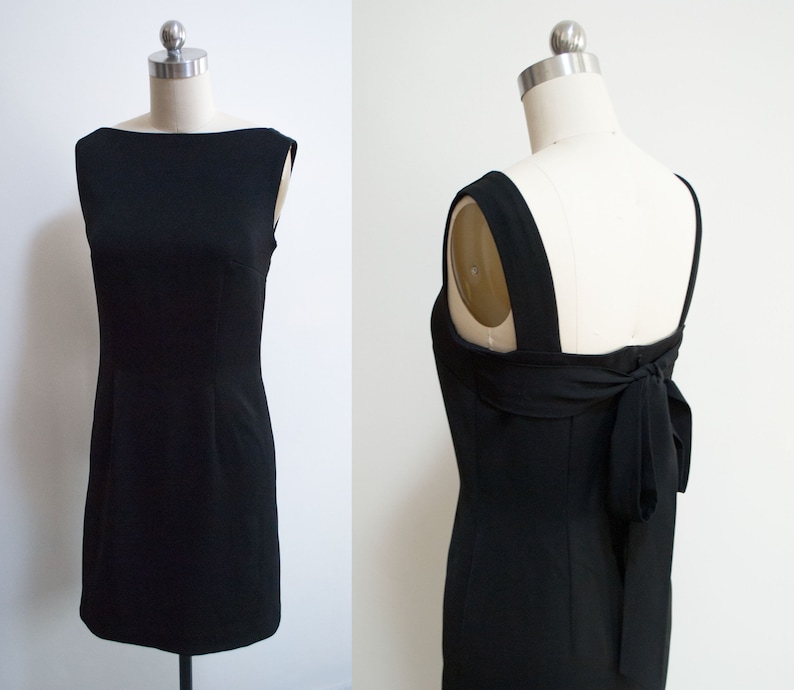 K&ouml;nnte beinhalten: Ein schwarzes &auml;rmelloses Kleid mit einem runden Ausschnitt und einer Schleife im R&uuml;cken.