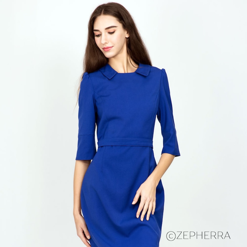 May include: A royal blue dress with a white collar and three-quarter sleeves. The dress has a fitted silhouette and a belt at the waist.