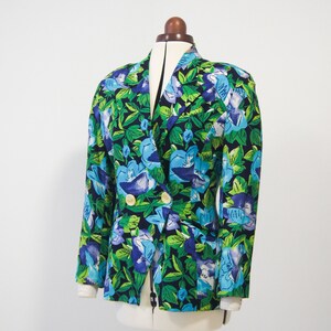 May include: A double-breasted blazer with a floral print featuring blue, green, and white flowers on a black background.