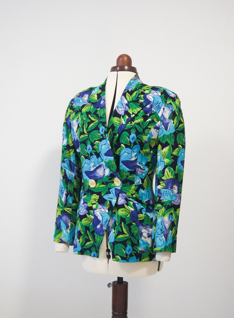 May include: A double-breasted blazer with a floral print featuring blue, green, and white flowers on a black background.