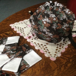 May include: Four black and white fabric coasters with white fabric backing. The coasters are on a wooden table with a white crocheted doily and a black and white floral teapot cozy.