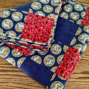 May include: A blue and red patchwork quilt with a pattern of stars and seals. The seals are gold and blue with the words "United States Army" and "Seal of the Army" on them.