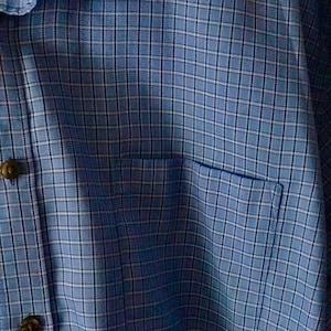 May include: A blue plaid shirt with a button-up collar and a pocket on the left side.
