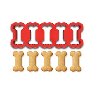 May include: A red plastic dog bone-shaped cookie cutter with five cutouts, and five baked dog biscuits. The biscuits are light brown and shaped like bones. The cutter is a solid red color and sits above the biscuits.