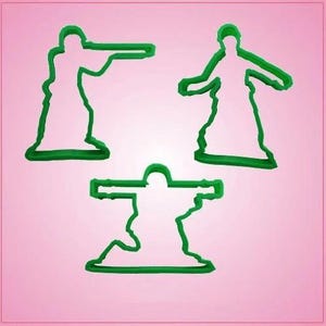 May include: Three green plastic cookie cutters in the shape of toy soldiers. One is aiming a rifle, another has arms outstretched, and the third is kneeling. The cookie cutters are on a pink background.