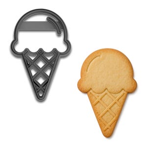 May include: An ice cream cone cookie cutter next to a baked ice cream cone cookie. The cookie cutter is dark gray and shaped like an ice cream cone. The baked cookie is light brown with a waffle cone design.