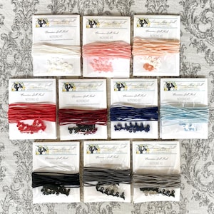 May include: Nine packages of doll making supplies, each containing a spool of thread, a set of plastic letters, and a set of plastic buttons. The packages are labeled "Lemon Bay Doll, Coronation Doll Kit, NOTIONS KIT".
