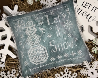 May include: A green and white embroidered pillow with a snowman and the text "Let it Snow".