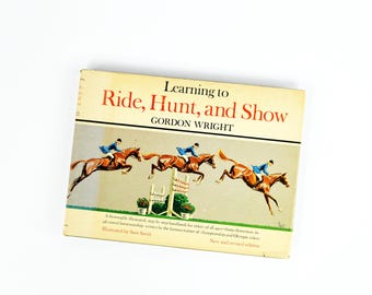 May include: A vintage book titled "Learning to Ride, Hunt, and Show" by Gordon Wright. The cover features illustrations of riders on brown horses jumping over obstacles. The book is a new and revised edition.