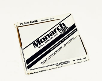 May include: A white box with black text that reads "Monarch Wall Mirror Tile" and "Plain Edge Mirror Tile". The box contains 12 inch by 12 inch mirror tiles. Made in the USA.