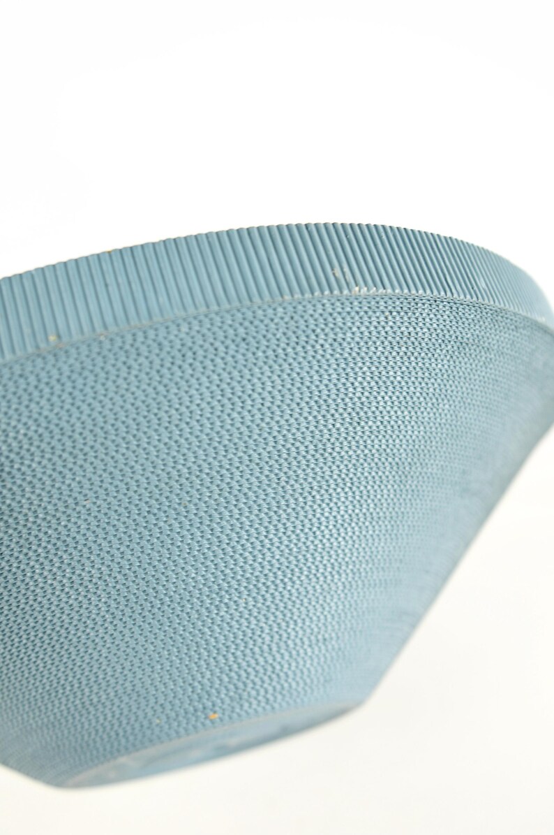 May include: Close-up of a light blue, textured bowl. The bowl has a woven pattern on the sides and a ribbed rim. The bowl is set against a white background.