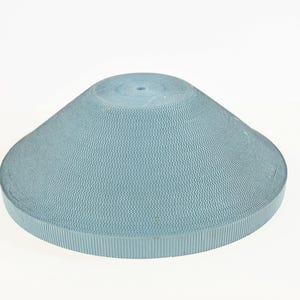 May include: A light blue, cone-shaped object with a textured surface and a small hole at the top. The object has a wide, flat base and a rounded top. The material appears to be a type of paper or cardboard.