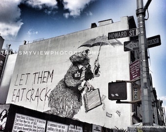 May include: A black and white illustration of a rat with a briefcase and the words "Let them eat crack" on a building wall. The building is in a city with street signs that read "Howard St", "One Way", and "No Standing 7am-7pm".
