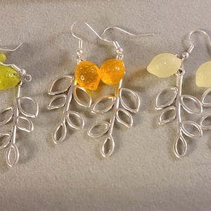 Puede incluir: Tres pares de pendientes de plata con diseños de hojas y abalorios de limón de vidrio. Los limones son verdes, naranjas y amarillos.