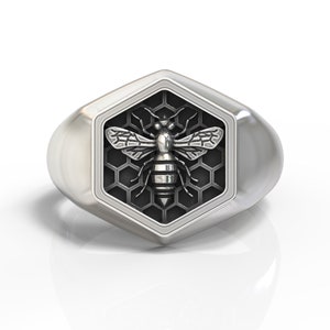 May include: A silver ring with a hexagonal design featuring a bee on a honeycomb background.