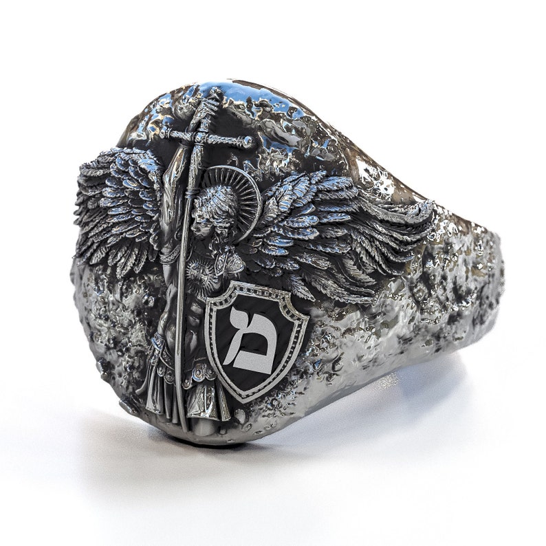 May include: A silver ring with a detailed design of an angel with wings holding a sword and a shield with the Hebrew letter 'Dalet' on it.