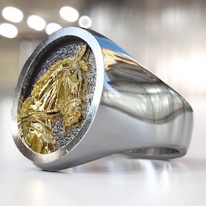 K&ouml;nnte beinhalten: Ein silberner Ring mit einem goldenen Pferdekopf-Design. Der Pferdekopf ist detailliert und hat eine gl&auml;nzende Oberfl&auml;che.