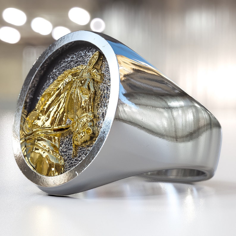 K&ouml;nnte beinhalten: Ein silberner Ring mit einem goldenen Pferdekopf-Design. Der Pferdekopf ist detailliert und hat eine gl&auml;nzende Oberfl&auml;che.