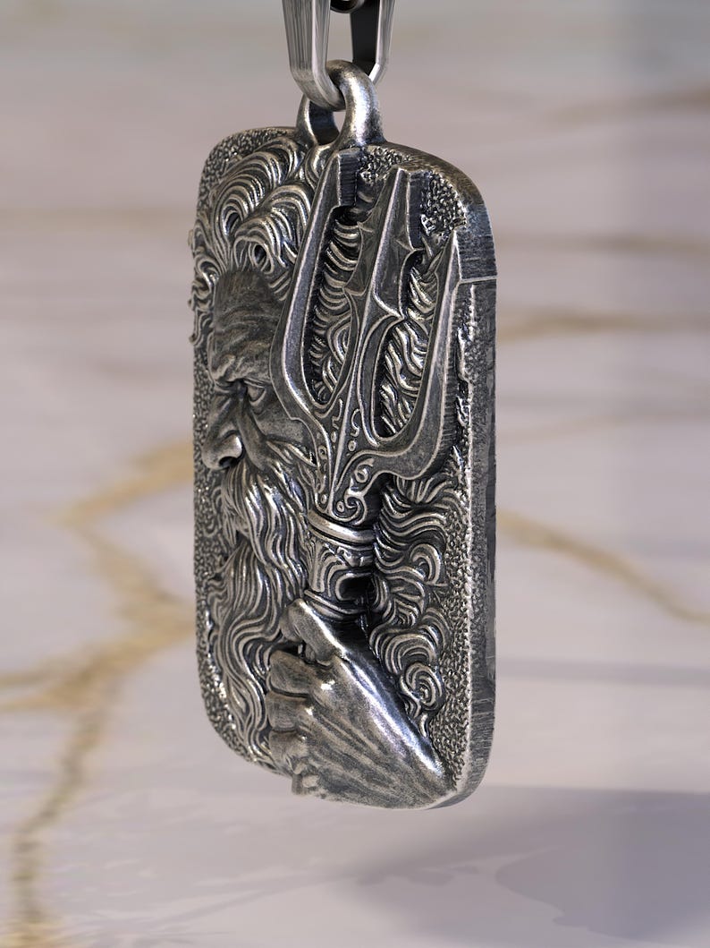 May include: A rectangular silver pendant featuring a detailed relief of a bearded man holding a trident. The pendant is suspended from a silver chain. The design has intricate details and a textured finish, suggesting a mythological theme.