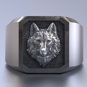 Op de afbeelding: Een zilveren ring met een wolfskopontwerp. De wolfskop bevindt zich in een vierkante vorm met een zwarte achtergrond.