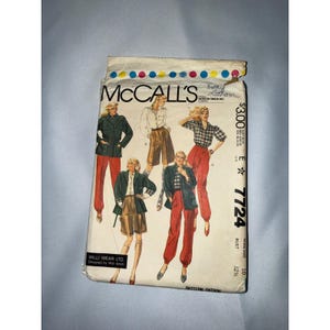 May include: A McCall's 7724 sewing pattern envelope featuring Willi Wear Ltd. designs. The cover displays illustrations of individuals wearing various combinations of jackets, shirts, and trousers in red, green, and plaid patterns, with the text 7724.