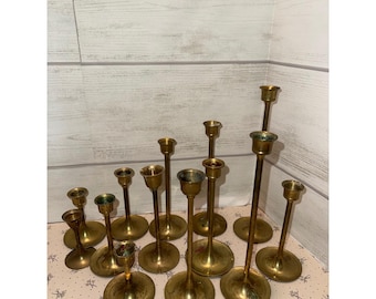 Conjunto de 13 castiçais vintage de latão com alturas graduadas para velas cônicas e centros de mesa.