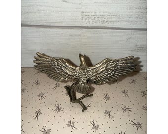 Estatueta vintage de águia em latão, empoleirada em um galho, representando um pássaro em pleno voo.