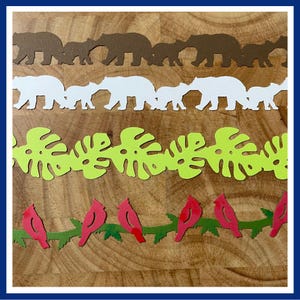 May include: Four horizontal paper die-cut strips. The top strip features brown bears, the second white bears, the third lime green monstera leaves, and the bottom strip displays red birds perched on a dark green branch, all arranged in a vertical stack.