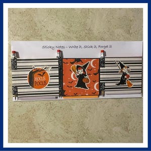 May include: A set of Halloween-themed sticky notes with black and white striped backgrounds. Each pad features a different design: a pumpkin with "Hocus Pocus", a witch holding a pumpkin, and a witch with a broom. The text "Sticky Notes - Write it, Stick it, Forget it" is above the pads.