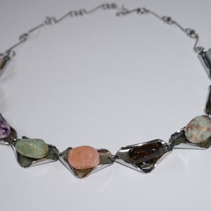 May include: A silver necklace with a variety of colorful stones set in silver triangular shapes.