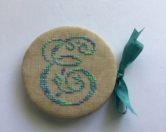 Cross stitched needle case with monogrammed letter “E” needle book.