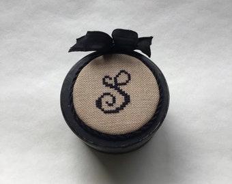 Black primitive button thimble box with cross stitched monogram letter “S”.