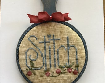 Cross stitched motif mounted on painted paddle board. Shepherds Bush design. Primitive stitching. Horn book.