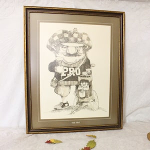May include: A framed black and white illustration of a golfer carrying a golf bag. The golfer is wearing a hat and a sweater with the word "PRO" on it. The image is titled "THE PRO".