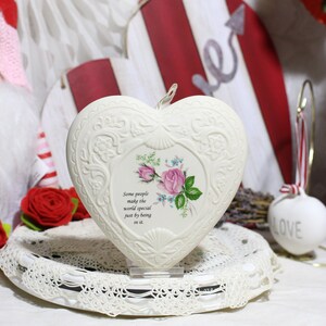 May include: White ceramic heart-shaped ornament with a floral design and the quote "Some people make the world special just by being in it."