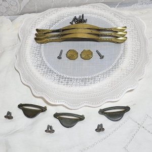May include: A set of vintage brass cabinet hardware, including three drawer pulls with ornate details and four smaller pulls with a simple design. The hardware comes with screws for installation.