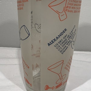 May include: A white glass cocktail shaker with a recipe for an Alexander cocktail printed on the side. The recipe calls for 1/3 dry gin, 1/3 creme de cacao, and 1/3 sweet cream. The shaker has a 12 ounce capacity.