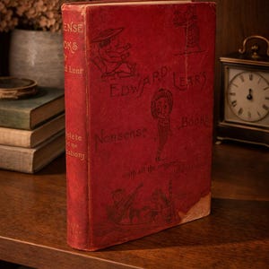 Puede incluir: Un libro rojo vintage titulado "Edward Lear's Nonsense Books" con ilustraciones. El libro se muestra en una estantería de madera, con un reloj y otros libros en el fondo. La portada tiene ilustraciones.